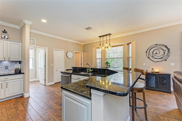 kitchen featuring wood-type flooring, sink, an island with sink, and white cabinets