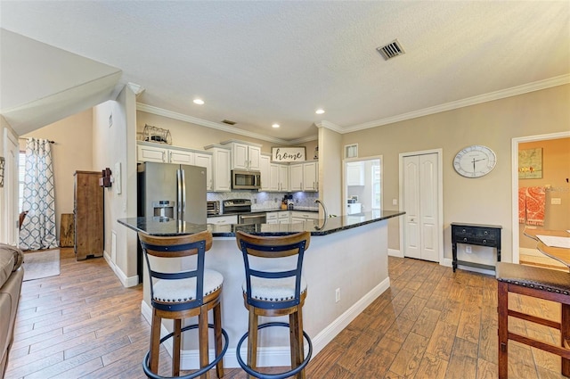 kitchen featuring appliances with stainless steel finishes, a breakfast bar, hardwood / wood-style floors, and decorative backsplash