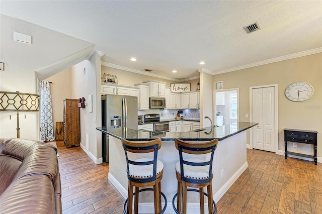 kitchen featuring tasteful backsplash, a kitchen bar, hardwood / wood-style floors, and appliances with stainless steel finishes