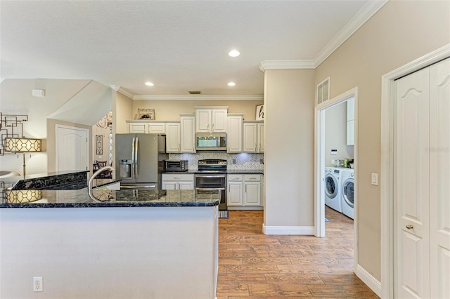 kitchen with washer and dryer, backsplash, light hardwood / wood-style floors, kitchen peninsula, and stainless steel appliances