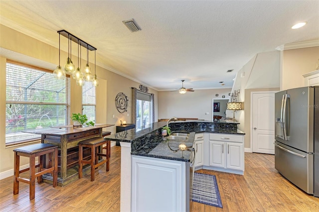 kitchen with sink, white cabinetry, stainless steel refrigerator with ice dispenser, ornamental molding, and light hardwood / wood-style floors