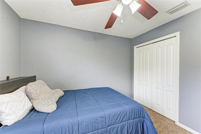 bedroom with carpet flooring, a textured ceiling, ceiling fan, and a closet