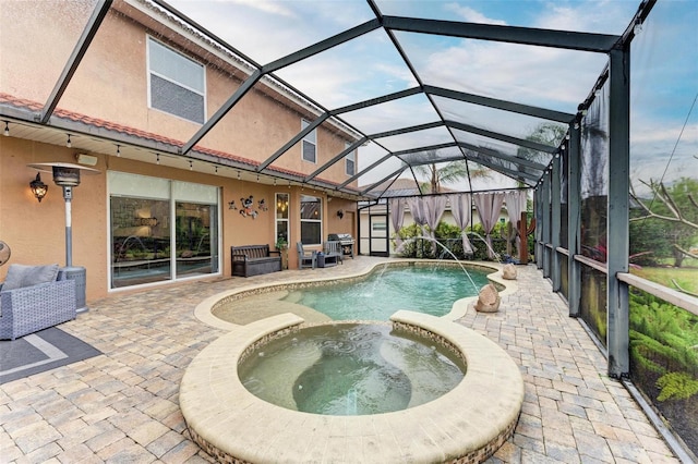 view of pool with a patio area, pool water feature, glass enclosure, and an in ground hot tub