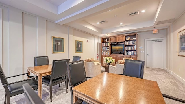 dining area featuring built in shelves, light colored carpet, and a raised ceiling