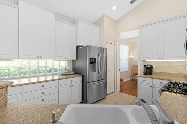 kitchen featuring white cabinetry, plenty of natural light, light tile patterned floors, and stainless steel fridge