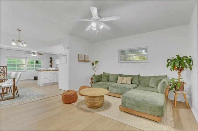 living room featuring ceiling fan with notable chandelier and light hardwood / wood-style flooring