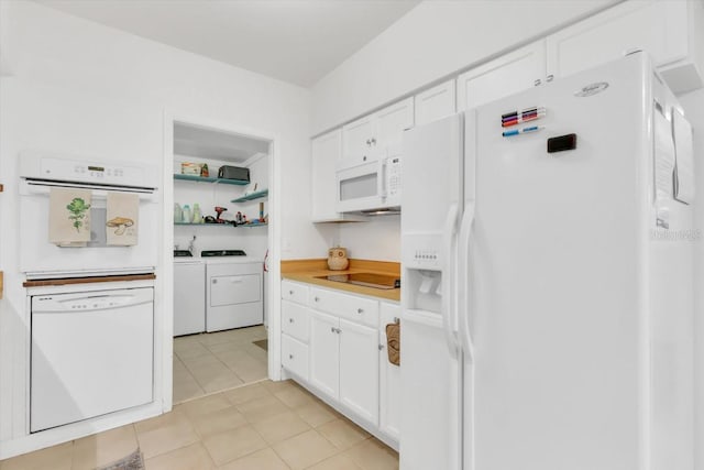 kitchen featuring light tile patterned flooring, white appliances, washing machine and dryer, and white cabinets