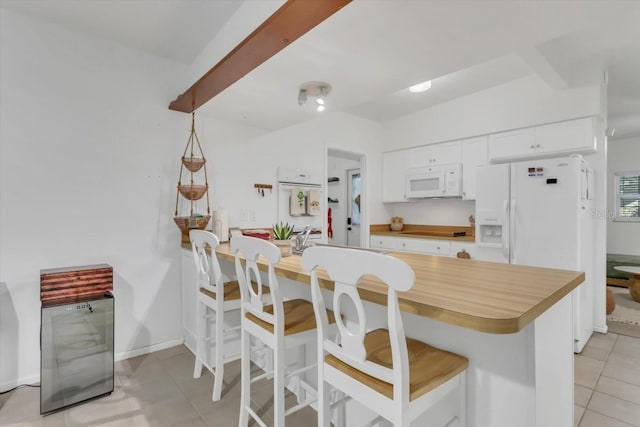 kitchen with a breakfast bar, white cabinets, white appliances, and kitchen peninsula