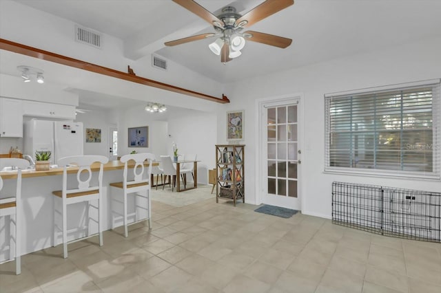 kitchen featuring a breakfast bar, white cabinetry, white refrigerator with ice dispenser, ceiling fan, and beam ceiling