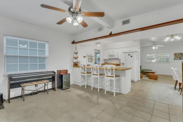 kitchen with a breakfast bar, white appliances, kitchen peninsula, ceiling fan, and white cabinets