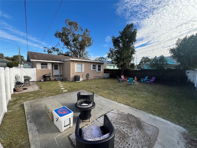 rear view of property with a patio, a lawn, and a fire pit