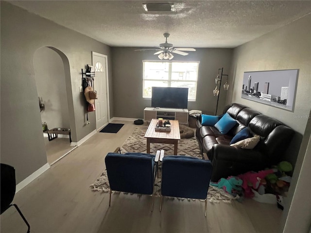 living room with ceiling fan, a textured ceiling, and light hardwood / wood-style floors