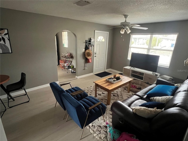 living room featuring ceiling fan, a textured ceiling, and light wood-type flooring