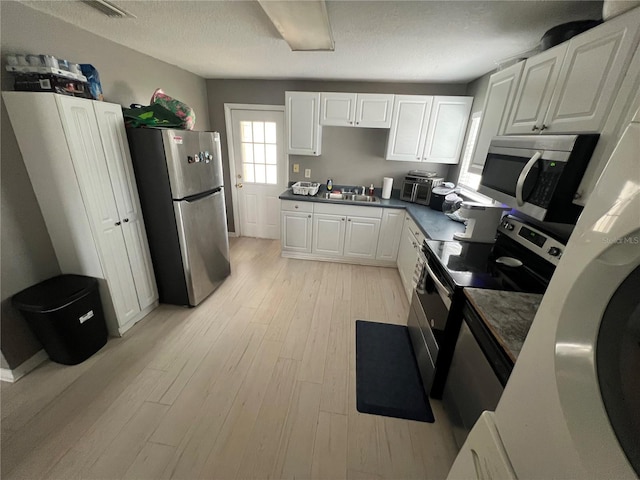 kitchen with white cabinetry, appliances with stainless steel finishes, and light wood-type flooring