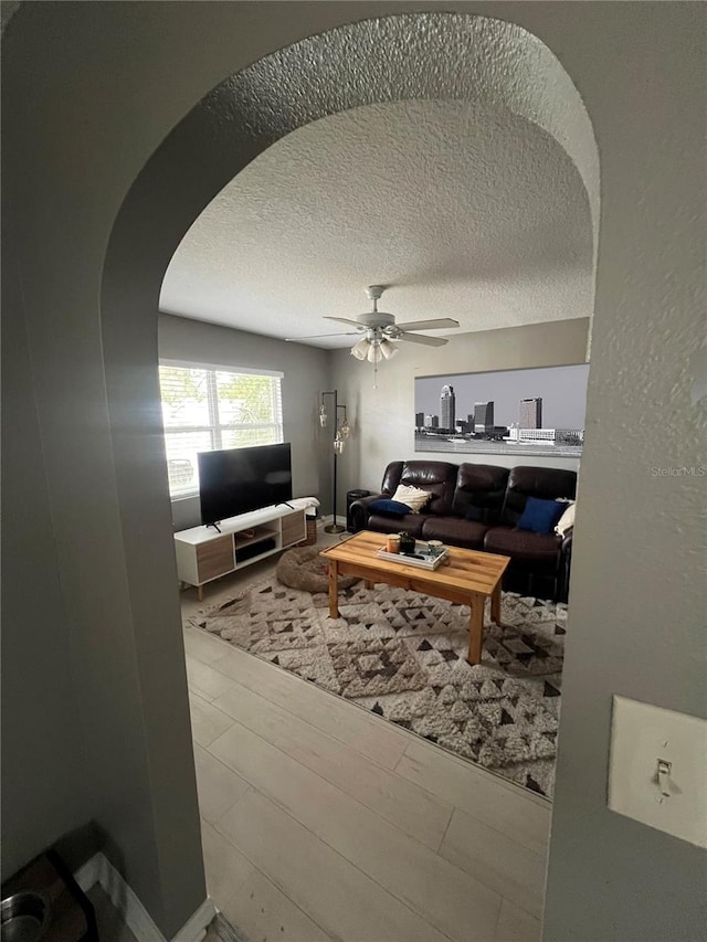 living room featuring ceiling fan, hardwood / wood-style floors, and a textured ceiling