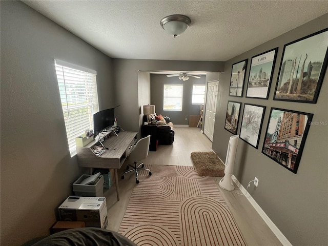 office area with ceiling fan, a textured ceiling, and light wood-type flooring