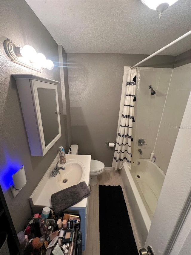 full bathroom with hardwood / wood-style flooring, vanity, shower / tub combo, toilet, and a textured ceiling