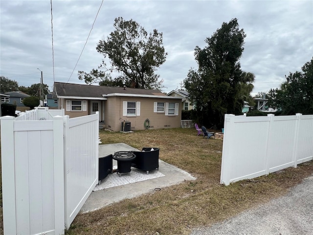 exterior space featuring a yard, central air condition unit, and a fire pit