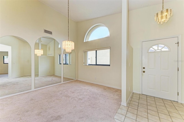 carpeted foyer entrance with a towering ceiling and an inviting chandelier