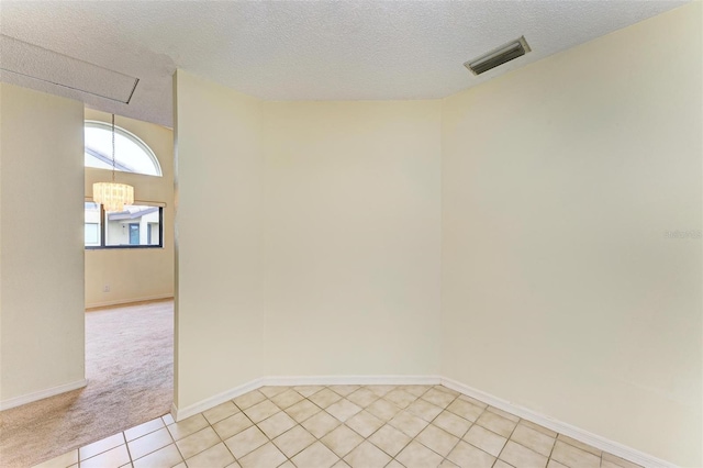 spare room featuring light tile patterned floors, a textured ceiling, and a chandelier