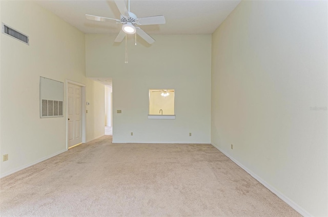 carpeted spare room with ceiling fan and a towering ceiling