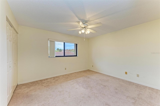 unfurnished bedroom featuring ceiling fan, light colored carpet, a closet, and a textured ceiling