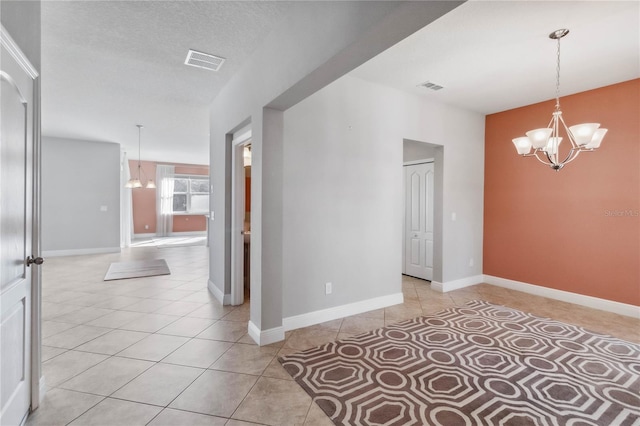 unfurnished room with light tile patterned flooring, a chandelier, and a textured ceiling