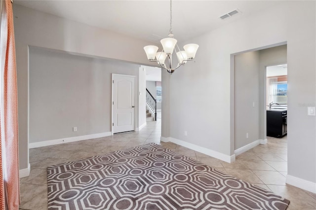 tiled empty room with an inviting chandelier