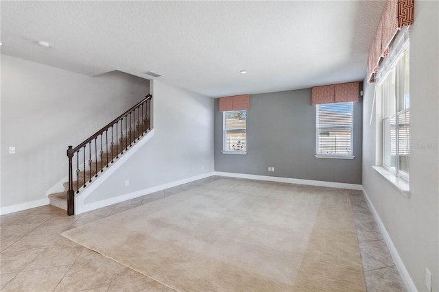 spare room featuring a textured ceiling and light tile patterned floors