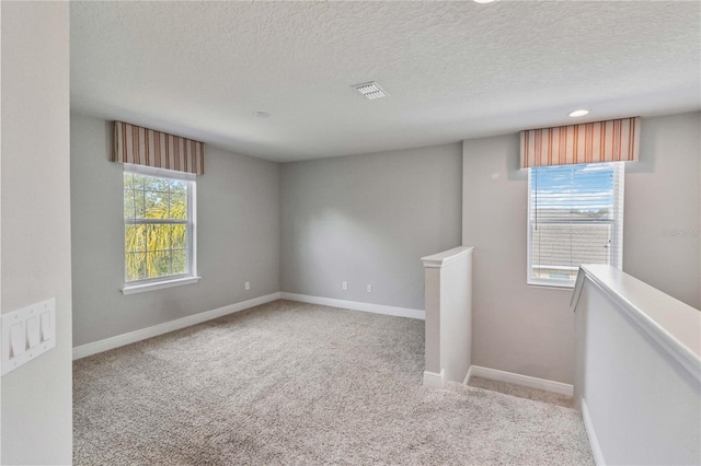 empty room featuring light carpet and a textured ceiling