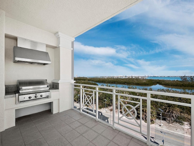 balcony with a water view, a grill, and exterior kitchen