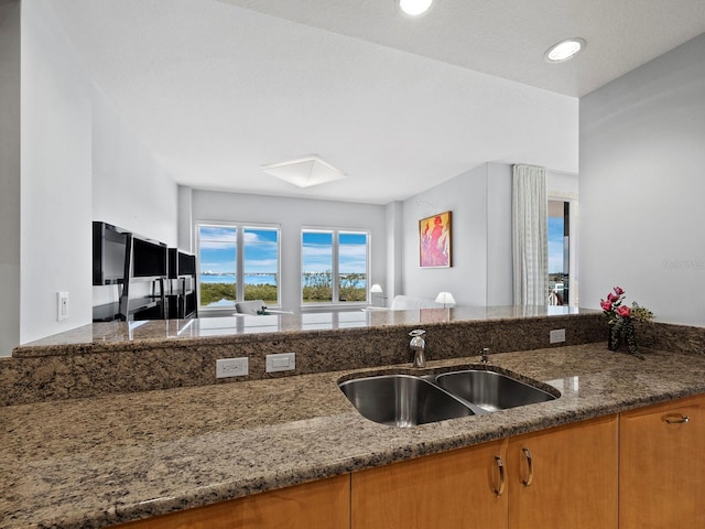 kitchen featuring sink, a skylight, and dark stone counters