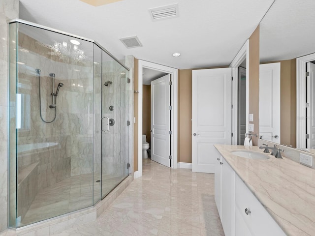 bathroom featuring vanity, a shower with door, and toilet