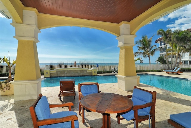 view of swimming pool featuring a patio and a water view