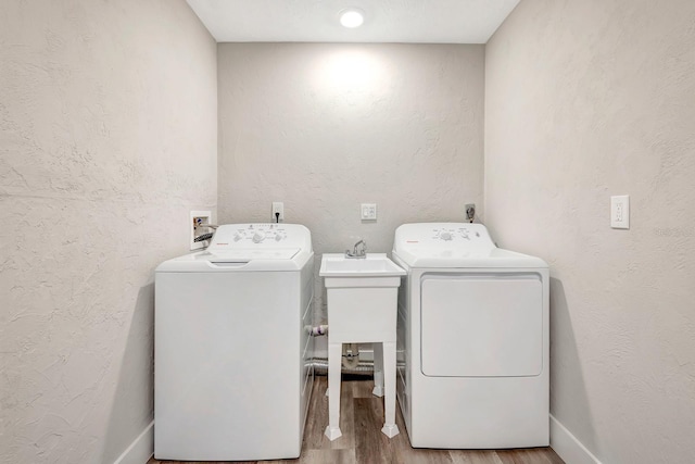 clothes washing area featuring sink, hardwood / wood-style flooring, and washing machine and dryer