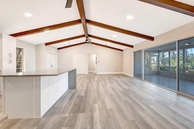 unfurnished living room featuring ceiling fan, light hardwood / wood-style floors, and lofted ceiling with beams