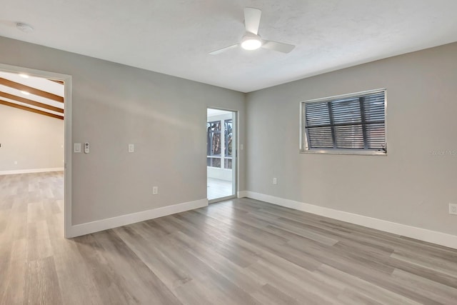 empty room with ceiling fan, light wood-type flooring, and beam ceiling