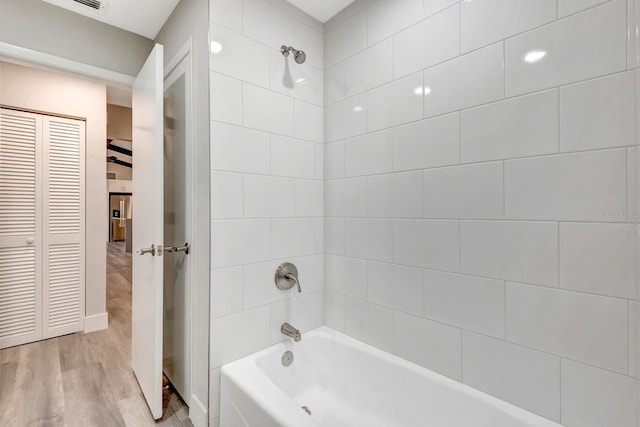 bathroom with hardwood / wood-style floors and tiled shower / bath combo