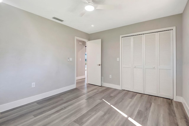 unfurnished bedroom with light wood-type flooring, ceiling fan, and a closet