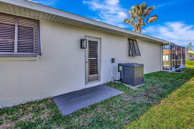 entrance to property with a yard, cooling unit, and a patio area