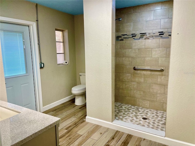 bathroom with tiled shower, vanity, and toilet