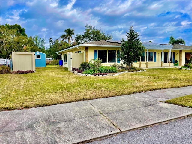 ranch-style house featuring a front lawn and a storage unit