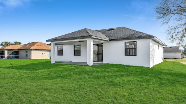 back of house featuring a shingled roof, a lawn, and stucco siding