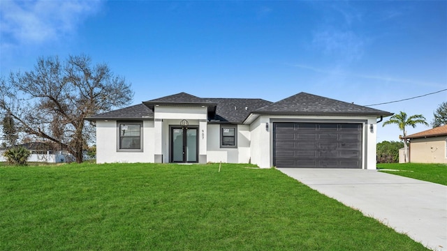 prairie-style home with a garage, driveway, roof with shingles, a front yard, and stucco siding