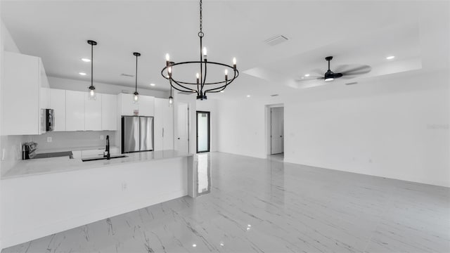 kitchen featuring pendant lighting, stainless steel appliances, open floor plan, white cabinetry, and a sink