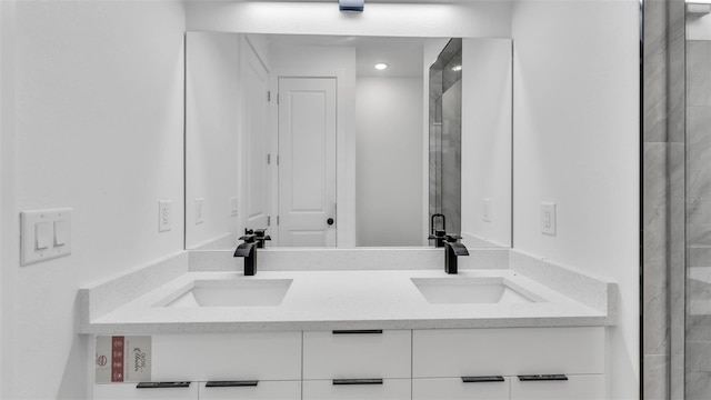 bathroom with a stall shower, a sink, and double vanity