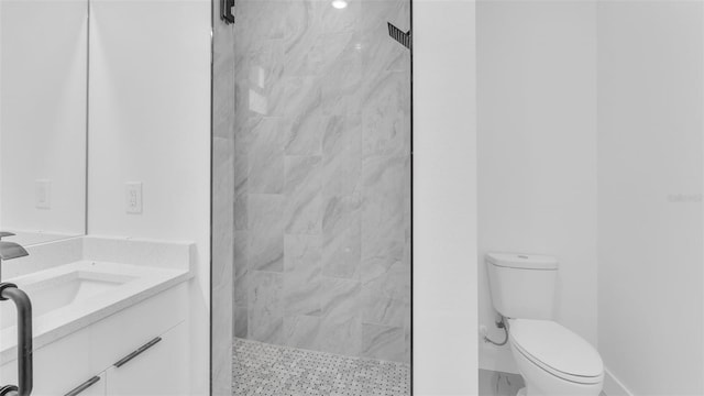 bathroom with vanity, a tile shower, and toilet