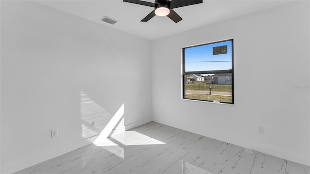 empty room with marble finish floor, ceiling fan, visible vents, and baseboards