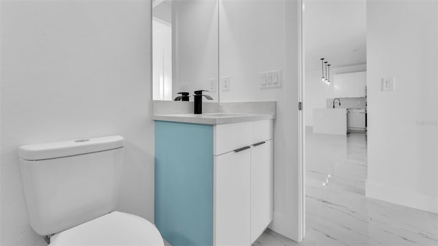 bathroom with marble finish floor, vanity, and toilet