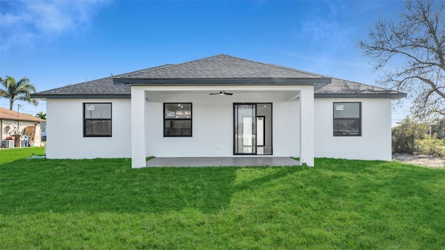 back of house with a lawn, a ceiling fan, and stucco siding